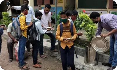  People receiving freshly served meals from volunteers during a community feeding drive 